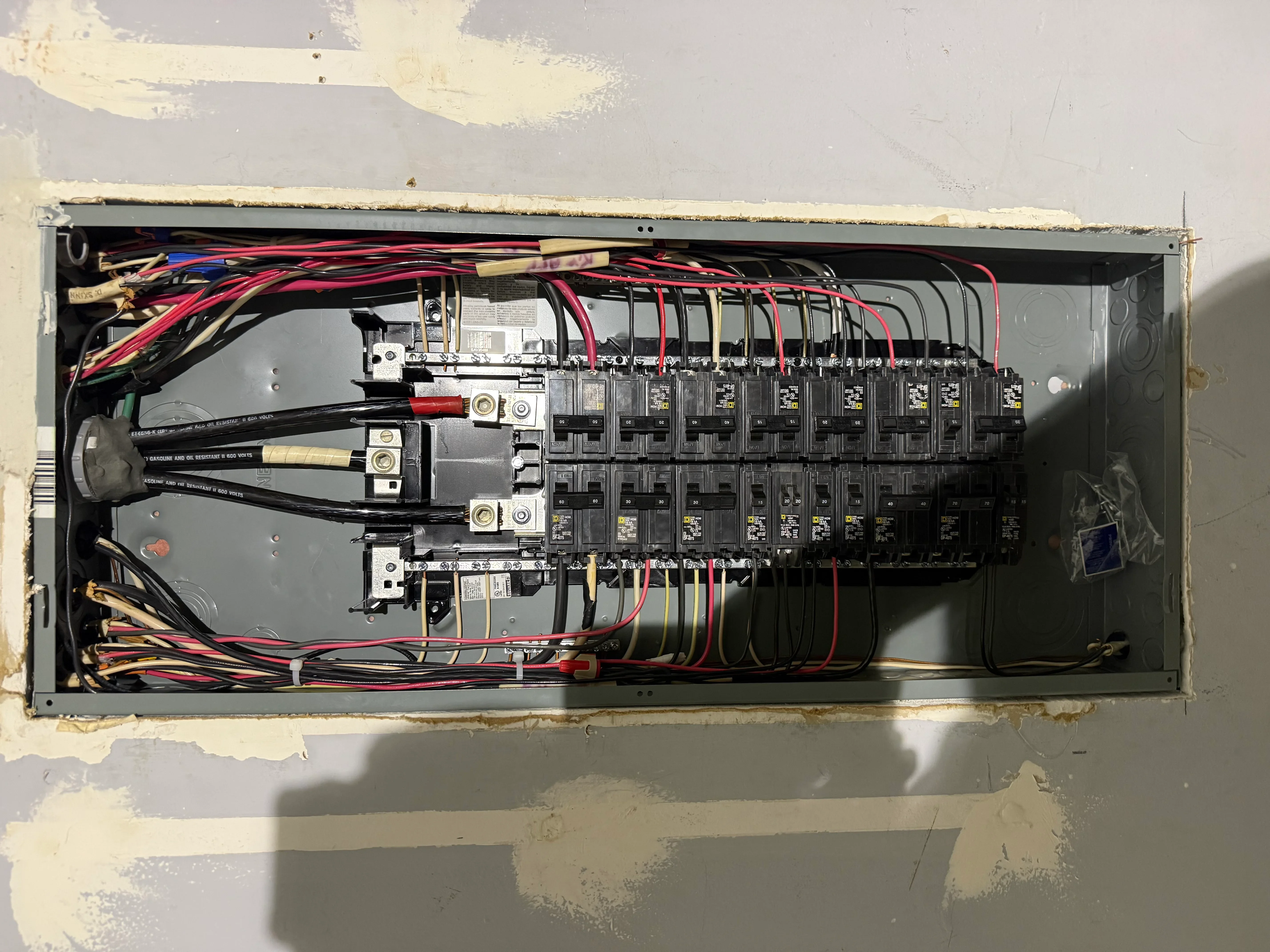 Electrical panel with organized breakers, copper wiring, and color-coded circuits installed in wall opening