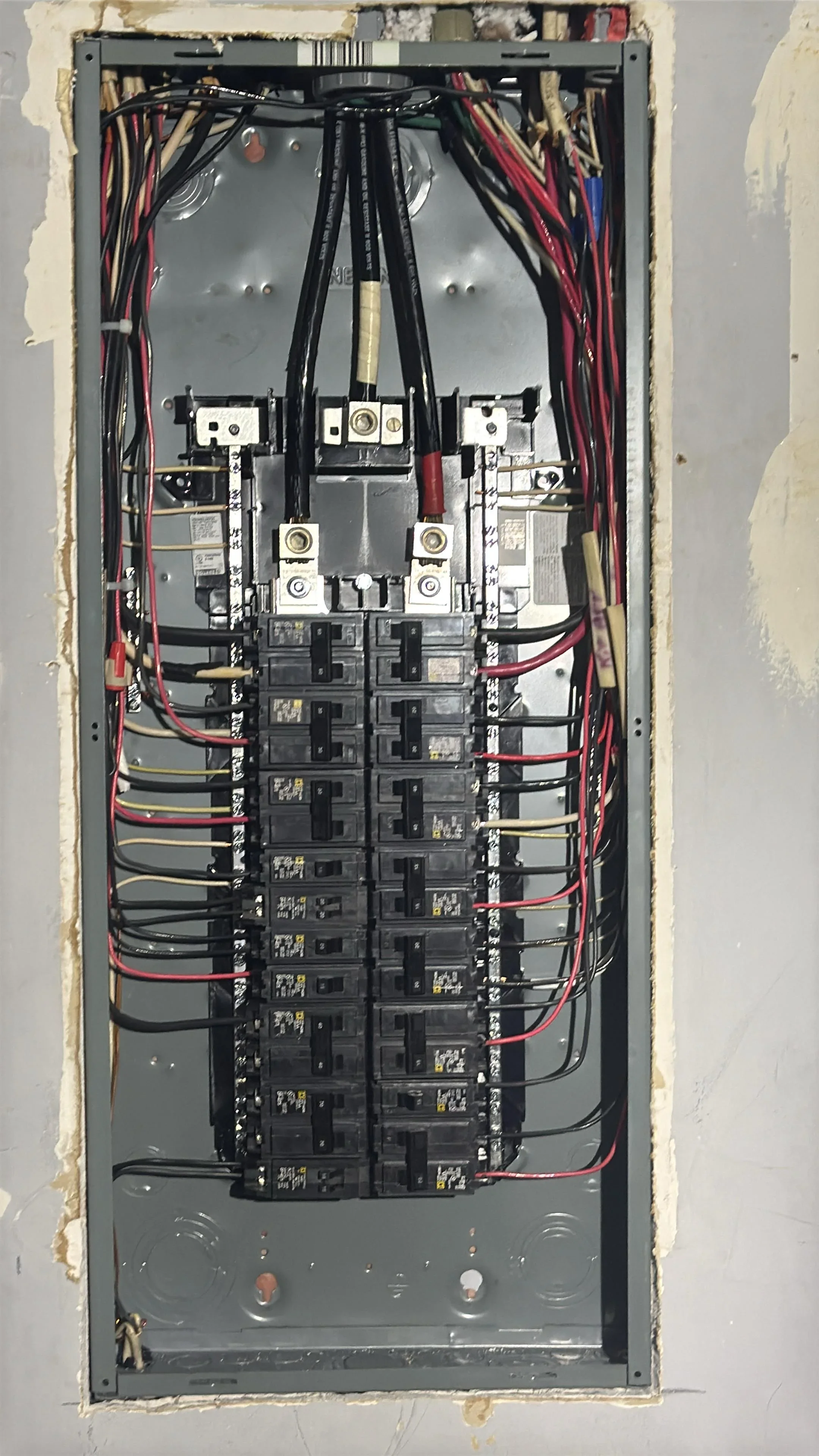 Electrical panel with breakers, red and black wiring, copper connections, and organized circuit layout