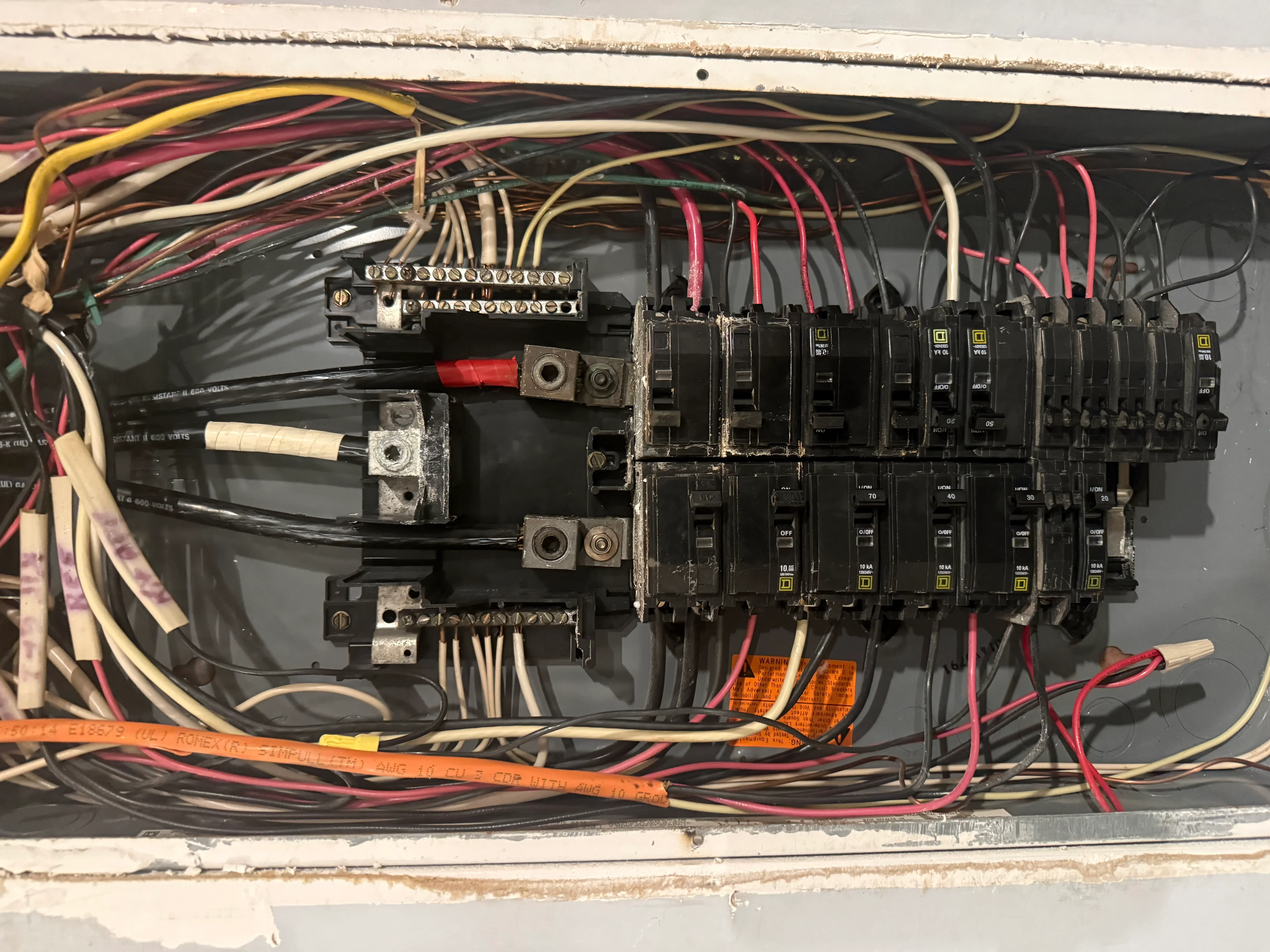 Electrical panel with breakers, copper bus bars, and color-coded wiring installation